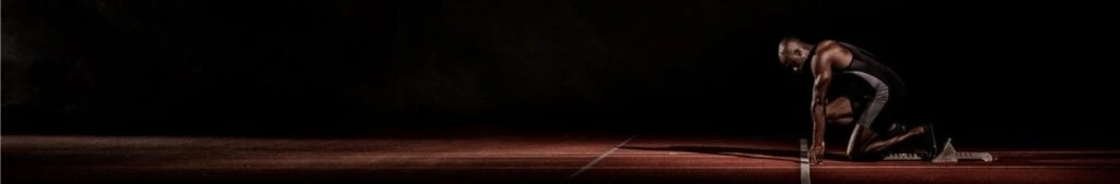 Athlete in starting position on a running track, emphasizing determination and readiness, relevant to strategies for brands to adapt and thrive during economic challenges.