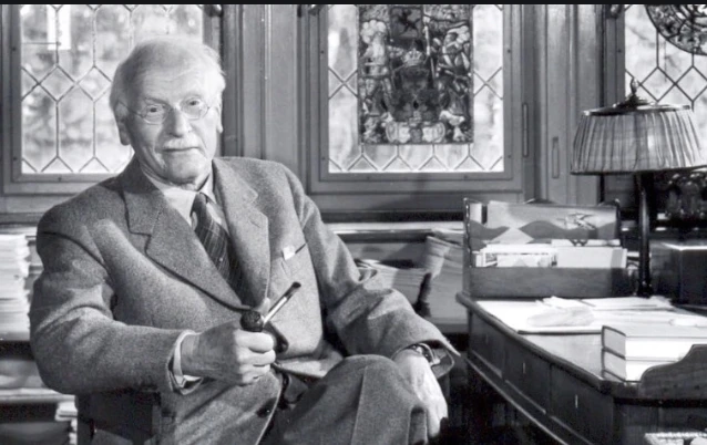 Carl Jung seated in a study, holding a pipe, surrounded by books and papers, highlighting his contributions to psychology and archetypes.