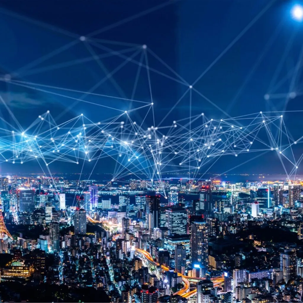 City skyline at night with illuminated buildings and interconnected lines representing a smart city communication network, symbolizing Big Data and IoT integration for enhanced market research insights.