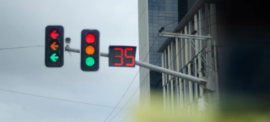Traffic light displaying green for left turn and red for straight, with countdown timer showing 35 seconds, symbolizing semiotic cues in urban environments.