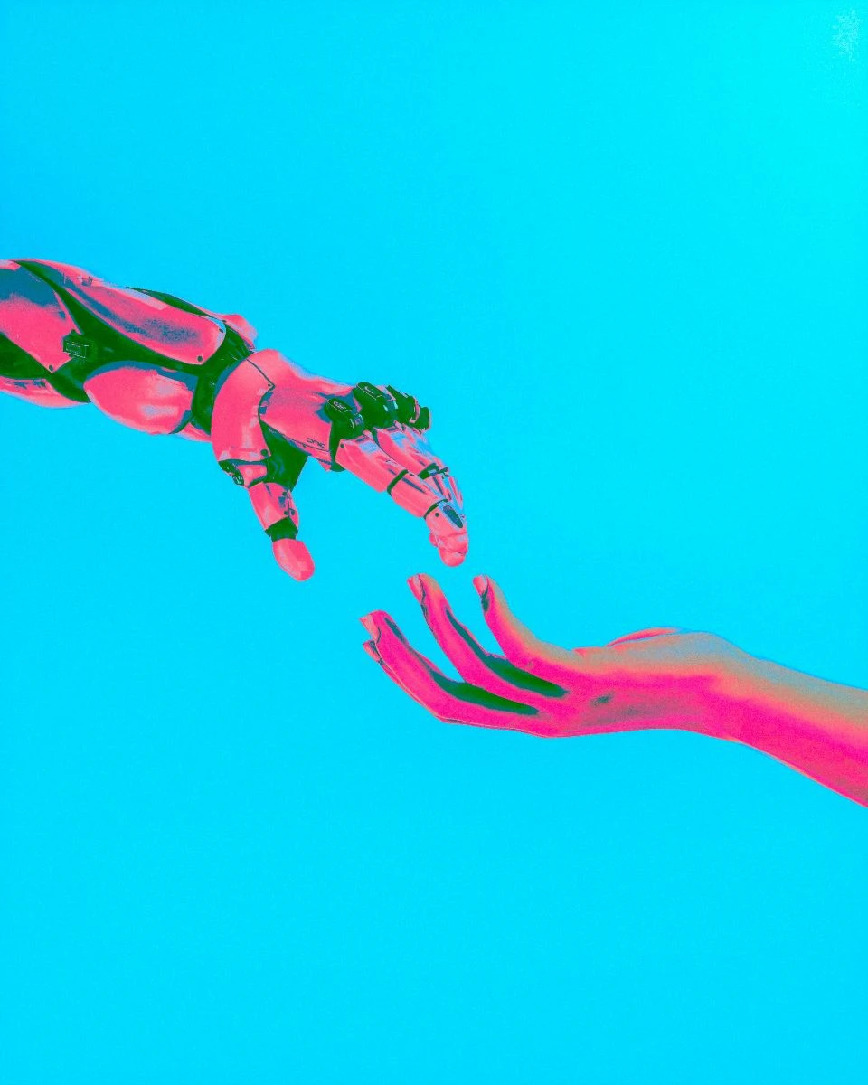 Robot hand reaching toward human hand against a bright blue background, symbolizing the integration of AI in market research and collaboration.